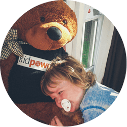 A preschooler cuddling a Kidpower teddy bear