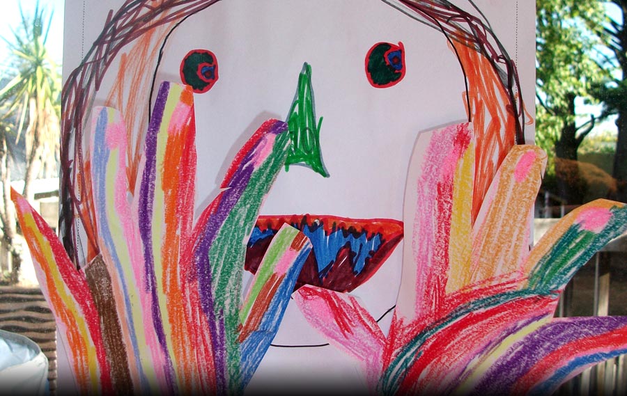 A picture drawn by a young child of a very colourful person putting their hands up and saying STOP